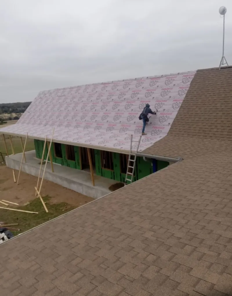 Worker preparing underlayment for a metal roof installation in Frankfort